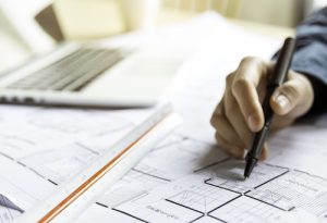 Close up woman hand working of Architect sketching project on blueprint at site construction work. Concept of architect, engineer in the office desk construction project banner